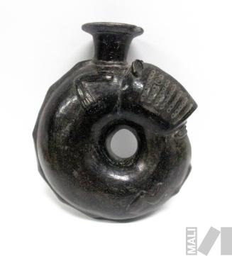 Cántaro que representa a un personaje zoomorfo que se encuentra comiéndose o mordiéndose la
cola